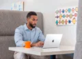Business professional using a laptop at a private workspace booth inside a modern business center
