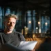 Alliance Virtual Offices vs Davinci Virtual Offices- Service Depth Cost Comparison for 2026 | Alliance Virtual Offices A focused professional reviews documents on a leather sofa inside a modern, warmly lit office space — the kind of presence a business address should project