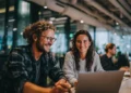 Two startup founders smiling while working together on a laptop in a modern shared workspace
