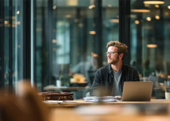 Solo attorney working on laptop in modern coworking space with glass walls and natural light