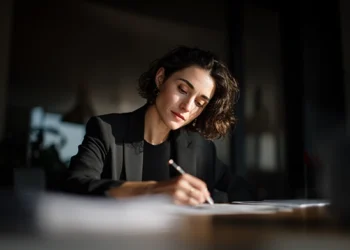 Female entrepreneur reviewing financial paperwork at her desk in a quiet office