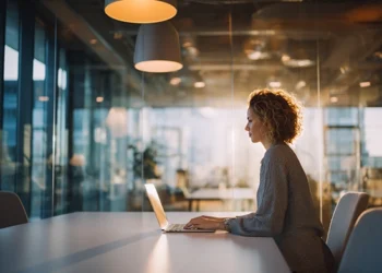 Professional working on a laptop in a client-ready meeting room with floor-to-ceiling glass walls