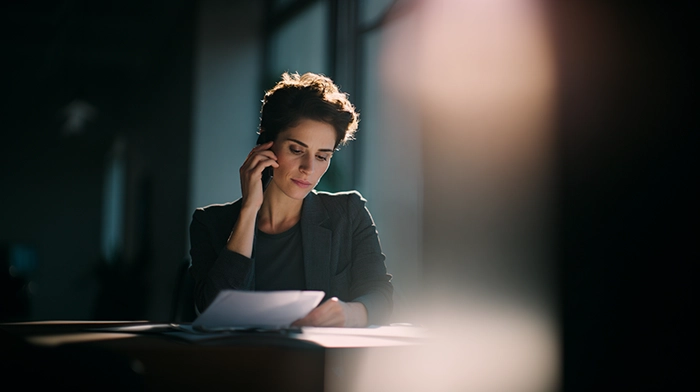 Tax Season Call Management for Accounting Firms- How to Handle the 300 Volume Spike | Alliance Virtual Offices Accountant reviewing tax documents while answering a client call during peak tax season