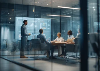A professional team collaborating in a sleek, glass-walled conference room, with one person presenting data on a large screen