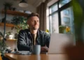 Small business owner working on a laptop from a home office with plants and natural light, representing why small businesses use a telephone answering service