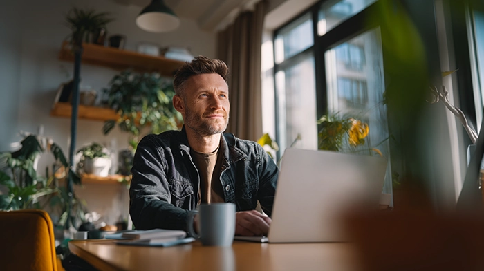 9 Reasons Small Businesses Use a Telephone Answering Service | Alliance Virtual Offices Small business owner working on a laptop from a home office with plants and natural light, representing why small businesses use a telephone answering service