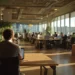Are Coworking Spaces Tax Deductible_ A 2026 Guide | Alliance Virtual Offices Professional working on a laptop in a sunlit coworking space with plants, shared desks, and other members collaborating in the background.