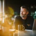 Small business owner sitting at a desk with a laptop and coffee mug, looking confident while considering AI answering service options for his company