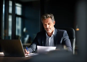 Business professional reviewing financial documents at a laptop in a modern office while building business credi