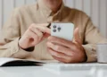 Person checking forwarded business calls on a smartphone at a desk with a notebook and coffee mug