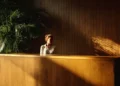 Receptionist at a wooden front desk in a professional virtual office lobby with warm natural lighting