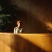 Receptionist at a wooden front desk in a professional virtual office lobby with warm natural lighting