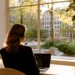 Answering Service Pricing- How Much Does a Business Live Answering Service Cost in 2026_ | Alliance Virtual Offices Woman wearing a headset working at a laptop by a large window, facing a sunlit garden and buildings in the late-afternoon light.