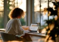 Woman managing business mail on a laptop at a sunlit home office desk