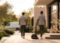 Cleaning business crew carrying supplies and a vacuum toward a client home at sunrise