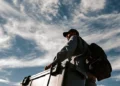 Medical courier with a backpack pushing a large insulated transport cooler outdoors