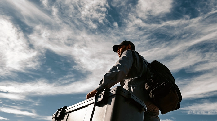 How to Start a Medical Courier Business- Licensing Contracts Setup Guide | Alliance Virtual Offices Medical courier with a backpack pushing a large insulated transport cooler outdoors