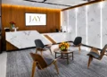 Reception and waiting area with a marble front desk, wood-panel wall, backlit marble panels, and four molded wood chairs around a round coffee table