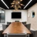 Conference Room Rental Atlanta- How to Book Professional Meeting Space | Alliance Virtual Offices Meeting room with wood conference table, gray chairs, wall-mounted screen, and round mirrors on a textured stone wall