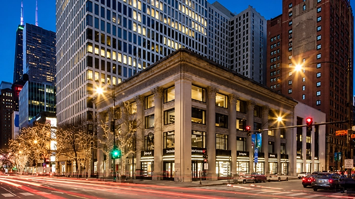 Conference Room Rental Chicago- How to Book Professional Meeting Space by the Hour | Alliance Virtual Offices Chicago street corner at night: classical columned building with ground-floor shops and office towers behind