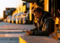 Logistics professional reviewing freight loads on a tablet beside a row of trucks at golden hour