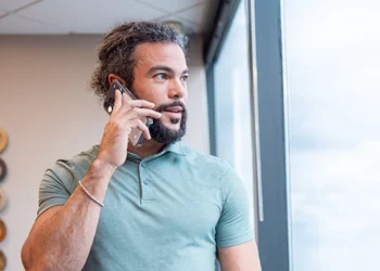 Small business owner taking a client call by the window in a private office