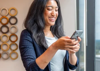 Business owner checking messages on her phone in a bright office space