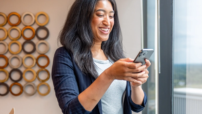 How to Get a Vanity Phone Number for Your Business 2026 Guide | Alliance Virtual Offices Business owner checking messages on her phone in a bright office space