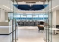 Executive office suite with a glass-walled boardroom, reception desk, and lounge seating