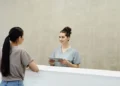Veterinary receptionist in scrubs holding a tablet and greeting a client at the front desk of a clinic