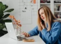 Woman on a business phone call while working on a laptop at her home office desk