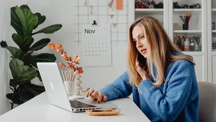 HIPAA-Compliant Phone Service for Therapists | Alliance Virtual Offices Woman on a business phone call while working on a laptop at her home office desk